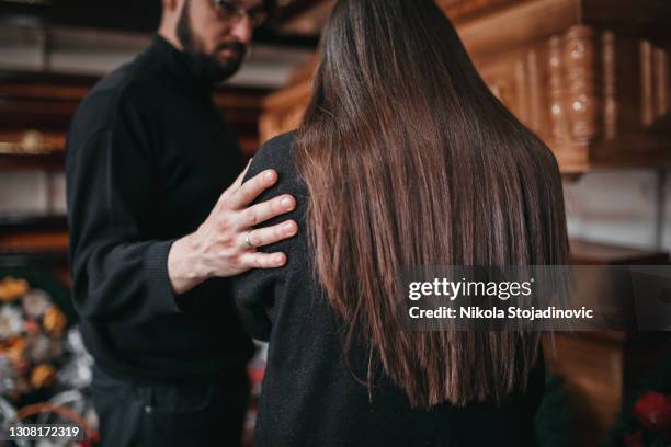 man comfort a woman in funeral parlor - funeral stock pictures, royalty-free photos & images