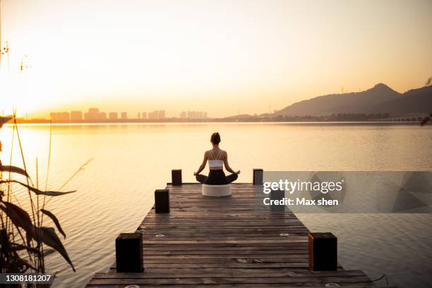 yoga player sitting at the pier facing to the lake - meditation stock pictures, royalty-free photos & images