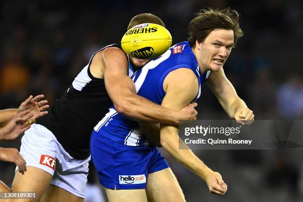 Jared Polec of the Kangaroos handballs whilst being tackled by Willem Drew of the Power during the round one AFL match between the North Melbourne...