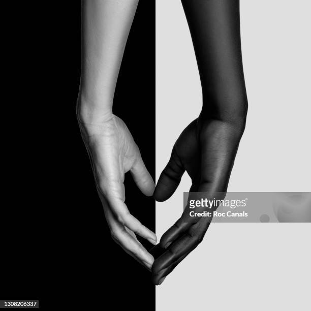 unity - black and white holding hands stock-fotos und bilder