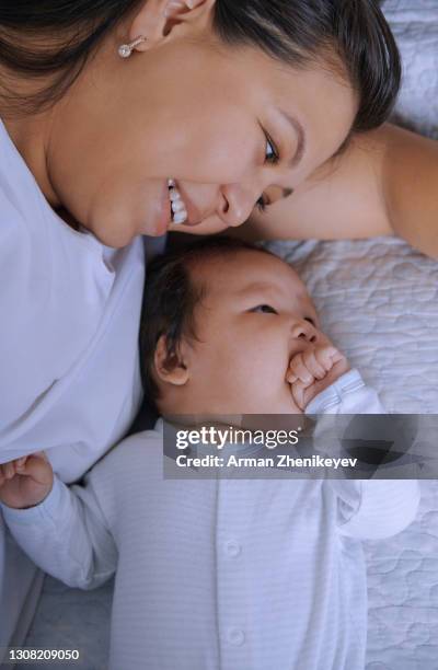 mother relaxing next to her newborn child - thumb sucking stock pictures, royalty-free photos & images