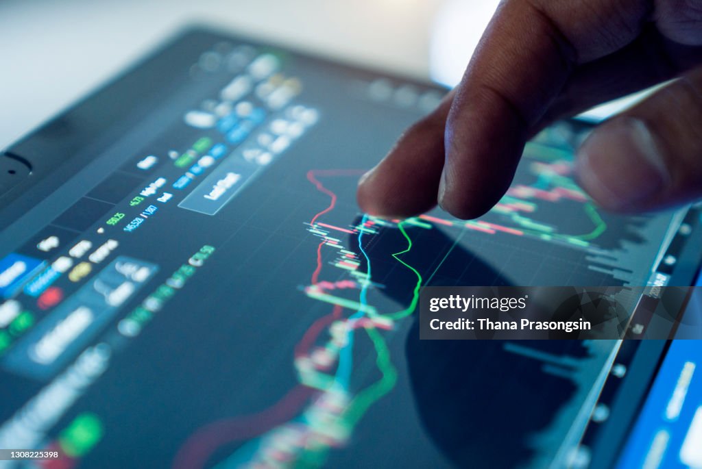 Market Analyze with Digital Monitor focus on tip of finger.