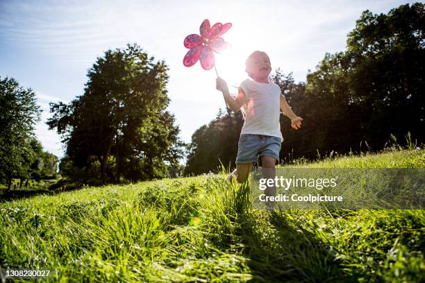 girl with pinwheel toy on a meadow - windrad natur wiese stock-fotos und bilder