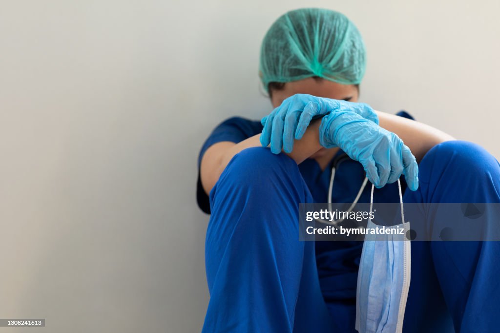 Gestresster müder Gesundheitsarbeiter sitzt auf dem Boden