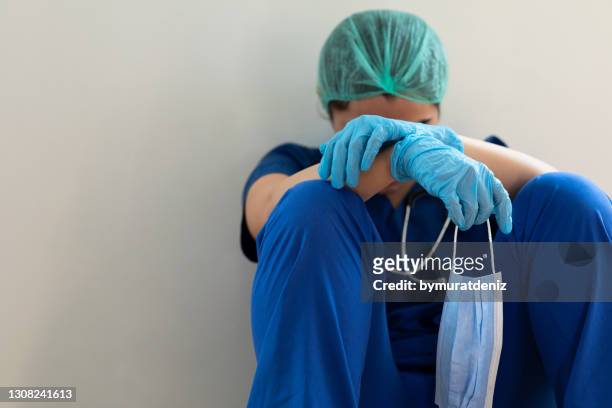 gestresster müder gesundheitsarbeiter sitzt auf dem boden - nurse stock-fotos und bilder