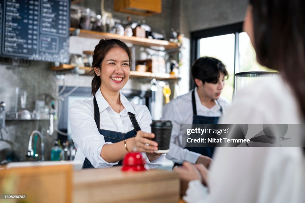 Shot of a Female barista serving a cup of coffee to a customer in a cafe counter. Small Business owner, Service mind and Customer service.