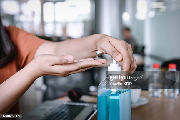 close-up of businesswoman having cleaning her hands with sanitizer in the office. - soap dispenser stock pictures, royalty-free photos & images