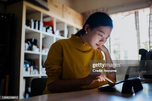 young asian woman working at home with digital tablet - e learning draw stock pictures, royalty-free photos & images