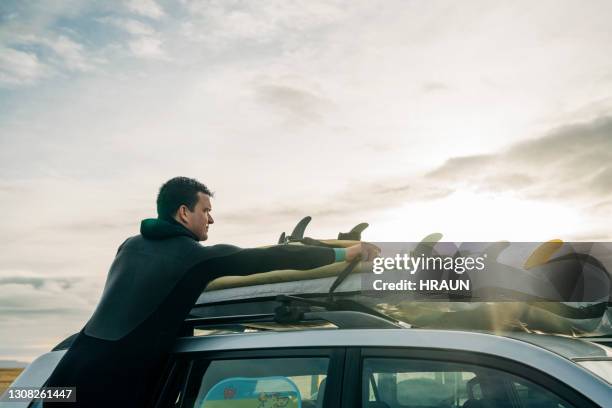 surfer loading his surfboard on car - loading car beach stock pictures, royalty-free photos & images