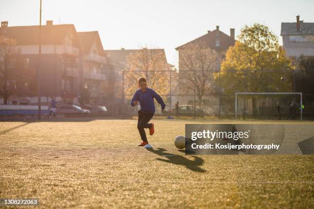 young boy chasing the ball - kicking tire stock pictures, royalty-free photos & images