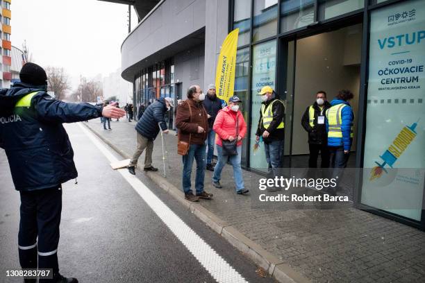 Police and municipal staff greet people to city vaccination centre at the National Football Stadium on March 21, 2021 in Bratislava, Slovakia. After...