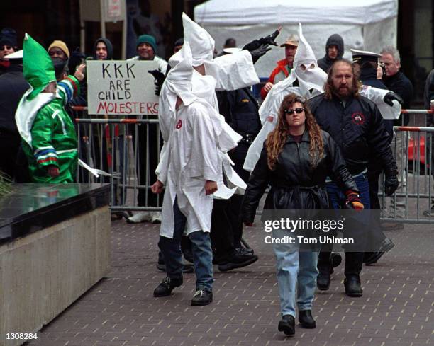 Members of the Ku Klux Klan are yelled by anti-Klan protesters December 2, 2000 as they go to erect a cross on Fountain Square in downtown...