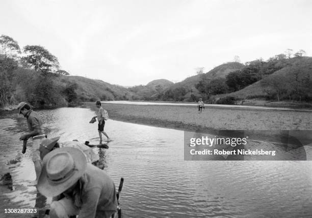 In territory held by the guerrilla faction Fuerzas Populares de Liberacion, FPL, armed guerrillas cross a river near the Salvadoran-Honduran border...
