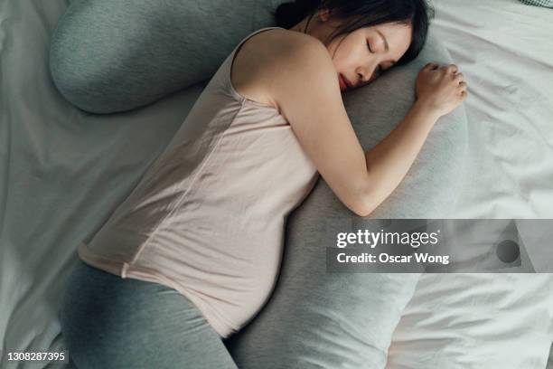 pregnant woman sleeping in bed with pillows - man sleeping pillow stock-fotos und bilder