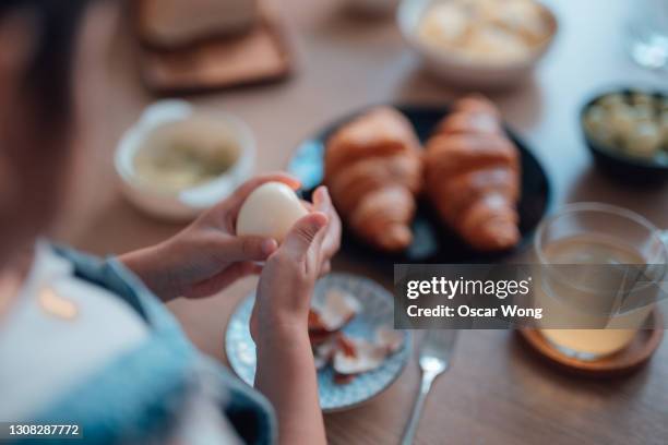 girl learning to peel hard boiled egg - boiled egg girl stock pictures, royalty-free photos & images