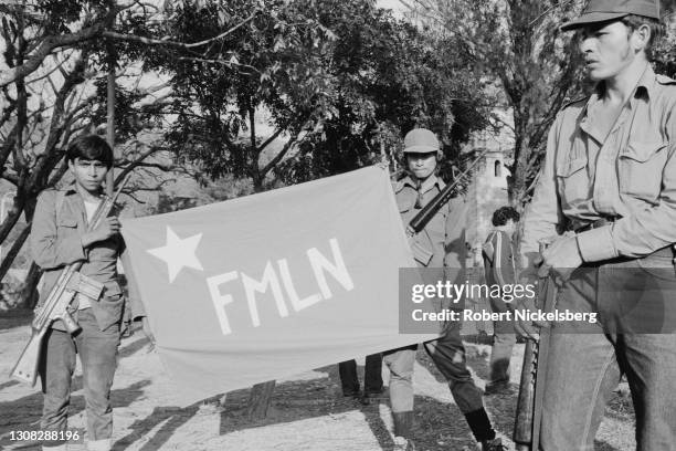 Fuerzas Populares de Liberacion guerrillas hold a banner, for the Frente Farabundo Marti para la Liberacion Nacional coalition, during a rally, La...
