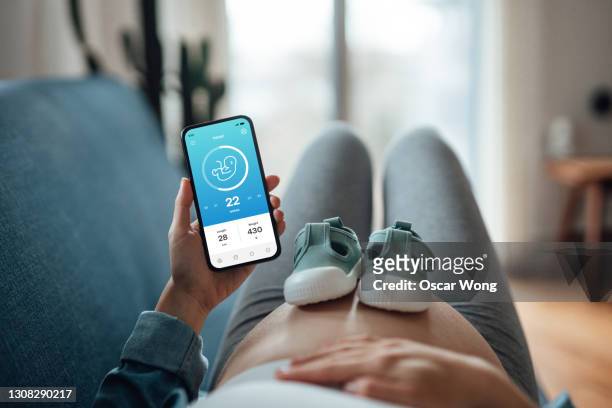 pregnant woman using telemedicine app on smartphone - future health care stockfoto's en -beelden