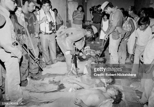 Journalist Raul Beltran interviews a Salvadoran Army officer as they and others stand over the bodies of dead civil defensemen, Verapaz, El Salvador,...