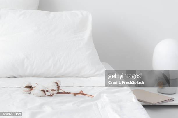 hotel bed with a cotton branch on duvet - sheet bedding stock pictures, royalty-free photos & images