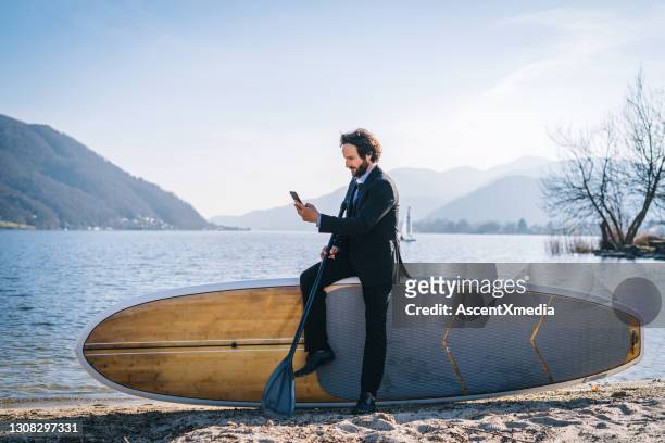business man talks on cellphone before paddle boarding in the morning - person surfing the internet stock pictures, royalty-free photos & images