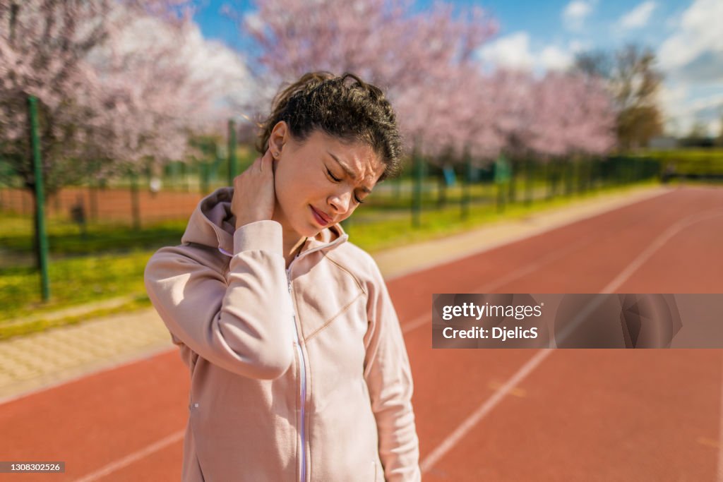 Sporty young woman having neck injury.