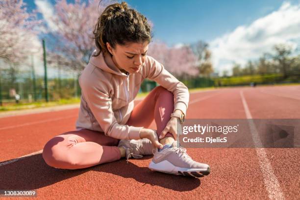 sporty young woman having ankle injury. - sprain stock pictures, royalty-free photos & images