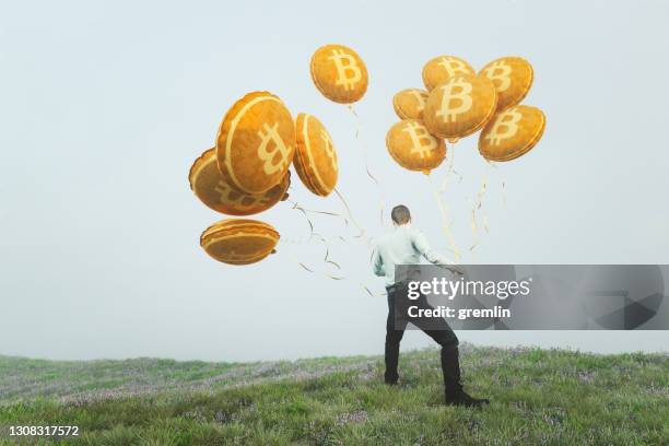 businessman grabbing and pulling bitcoin balloons - bitcoin stock pictures, royalty-free photos & images