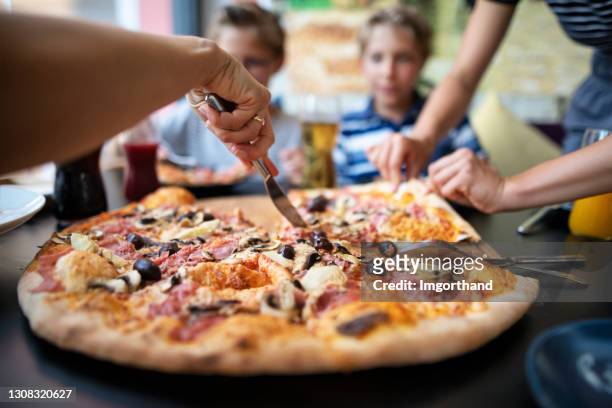 niños disfrutando de pizza en un restaurante - pizza fotografías e imágenes de stock