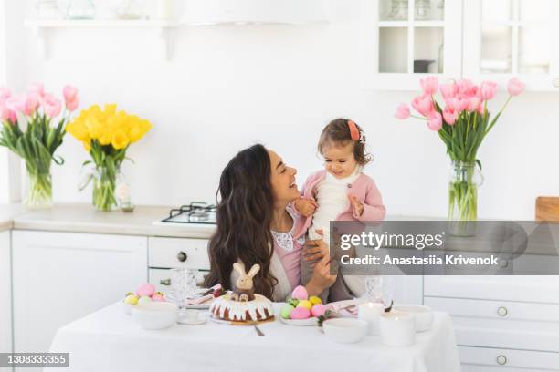 beautiful mother with cute little daughter celebrating easter at home. - easter breakfast stock pictures, royalty-free photos & images