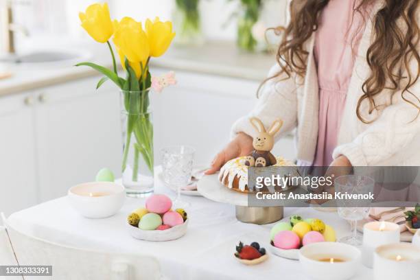 woman served dinner table with delicious homemade easter bundt cake and multicoloured easter eggs. - paasbrunch stockfoto's en -beelden