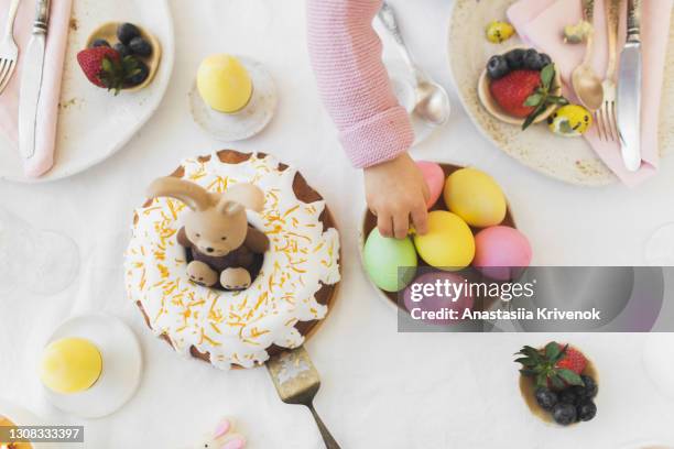 close up photo of kids hand takes an egg from easter table. - paasontbijt stockfoto's en -beelden