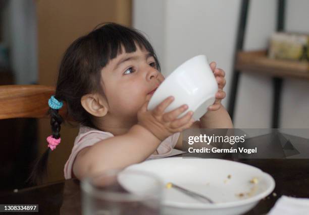 cute and hungry toddler girl eating last drop of her meal - girl eating in santiago stock-fotos und bilder