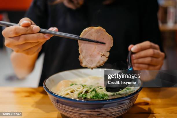 junge frau isst eine schüssel mit japanischen ramen mit essstäbchen - char siu pork stock-fotos und bilder