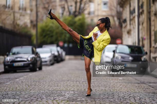 Emilie Joseph @in_fashionwetrust wears sunglasses, a white crew neck t-shirt from HM, a yellow oversized blazer jacket from Zara Man, sporty /...