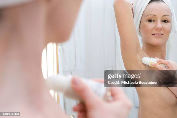young woman putting on deodorant in the bathroom - deo frau badezimmer stock-fotos und bilder