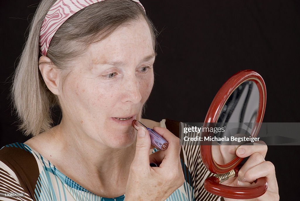 Woman, older than 65 years, putting on makeup
