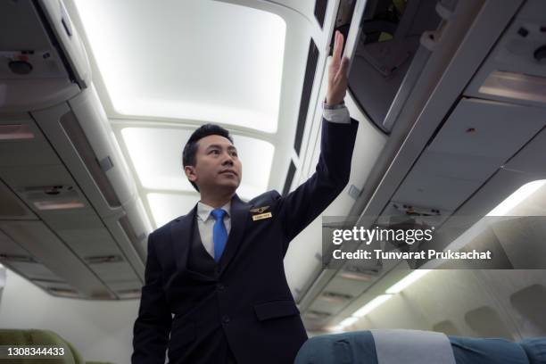 confident asian male pilot in uniform standing at the passenger seat inside of the airplane . - tripulação imagens e fotografias de stock