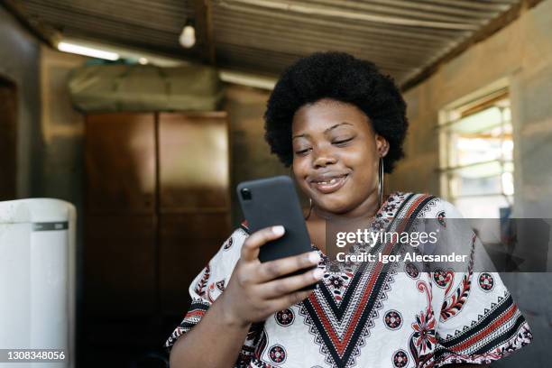 african woman using smartphone at home - third world stock pictures, royalty-free photos & images