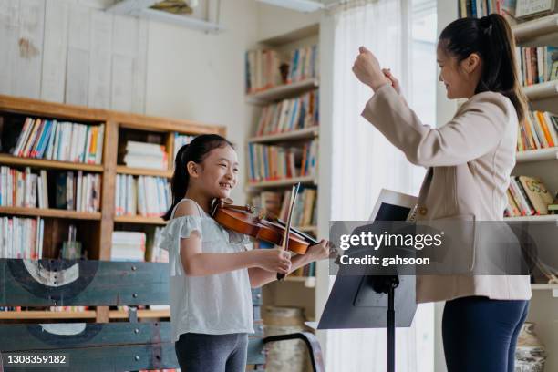 teacher conducting violin student in music class - kid conductor stock pictures, royalty-free photos & images