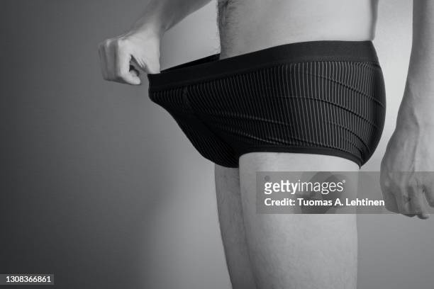 adult caucasian man pulling his black boxers with a hand. - parte del cuerpo humano fotos fotografías e imágenes de stock