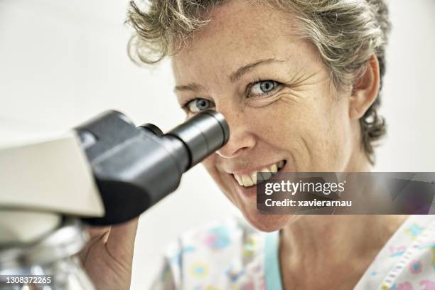 close-up of cheerful female veterinarian using microscope - medical technologist stock pictures, royalty-free photos & images