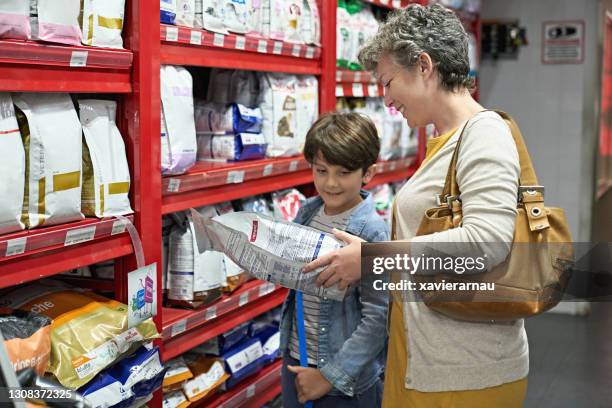 mutter und kleiner sohn kaufen hundefutter im pet shop - haustierfutter stock-fotos und bilder