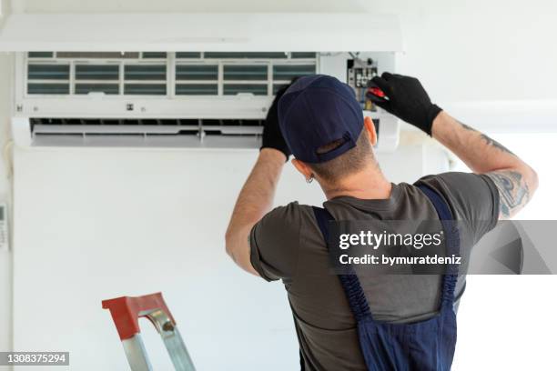 técnico reparando aire acondicionado - instalador fotografías e imágenes de stock