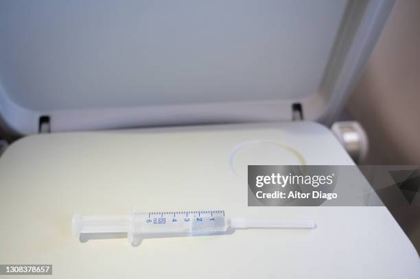 syringe with vaccine on a passenger's seat tray inside an airplane. - airplane tray table stock pictures, royalty-free photos & images