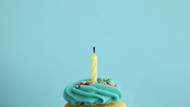 Birthday greetings concept. Blow out candle on muffin, cupcake. Blue background