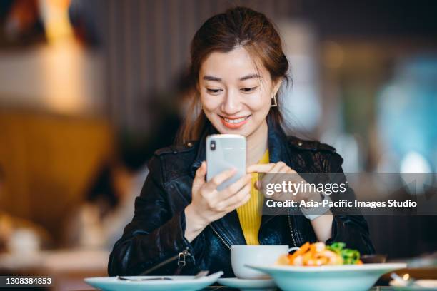 asian young woman using mobile phone in restaurant. - restaurant manager phone stock pictures, royalty-free photos & images