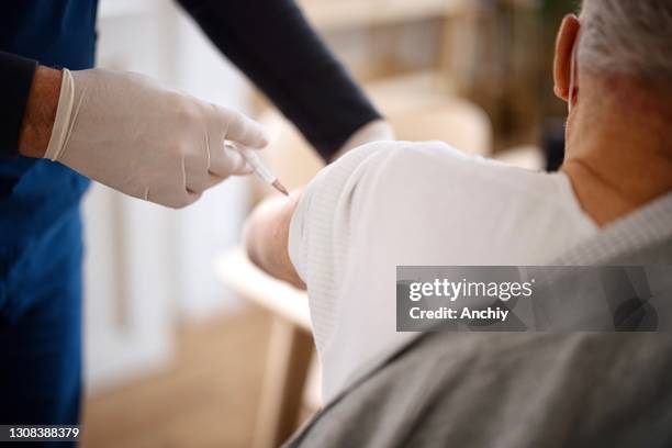 close up of a senior man wearing face protective mask while receiving vaccine at home - subcutaneous stock pictures, royalty-free photos & images