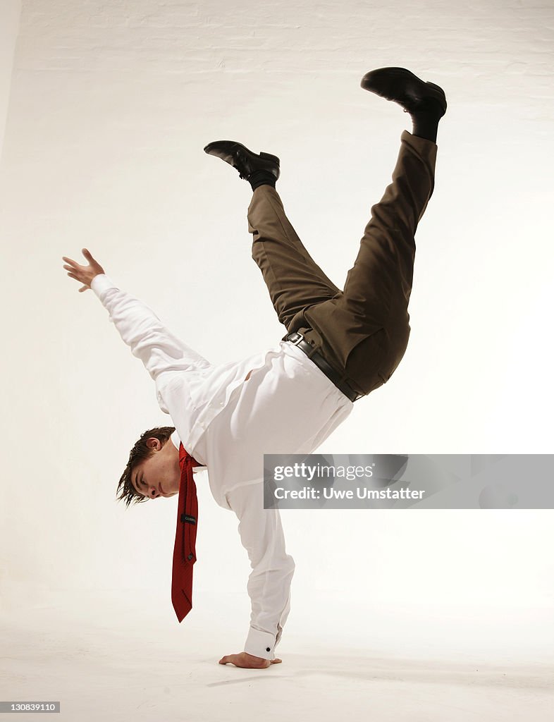 Young businessman doing a handstand with one hand