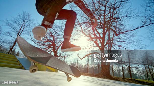 niedriger teil des jungen mannes, der stunt in skateboard park - unterer teil stock-fotos und bilder