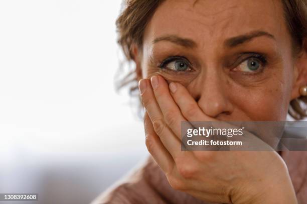 headshot of worried mature woman covering mouth with her hand - mão na boca imagens e fotografias de stock